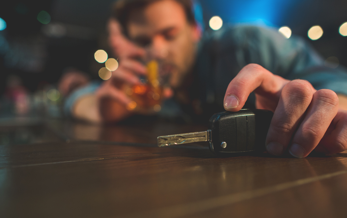 Man drinking at bar looking at car keys